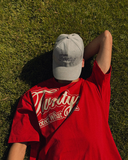 Person wearing a red shirt and gray cap lying on grass